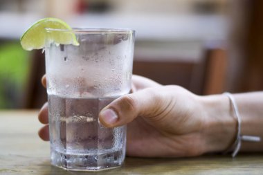 Erkek, su bardağını tutuyor.