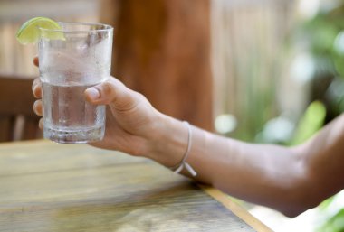 Erkek, su bardağını tutuyor.