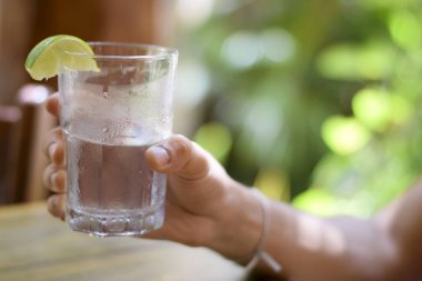 Erkek, su bardağını tutuyor.