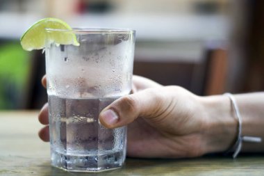 Erkek, su bardağını tutuyor.