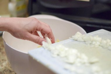 Kesme tahtasından doğranmış soğanlar el kazıyor