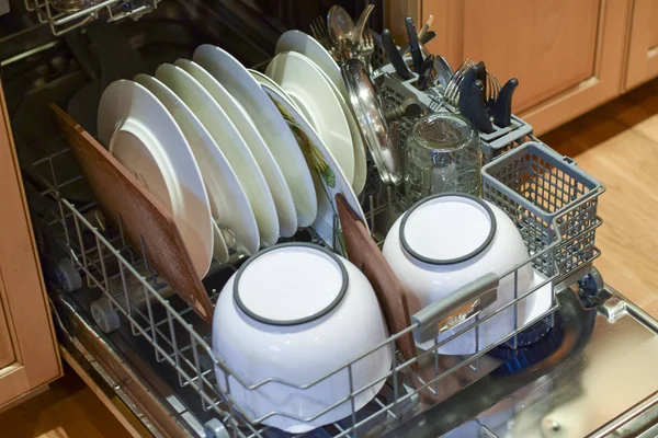 Женщина загружает посуду и столовое серебро в посудомоечную машину — стоковое фото