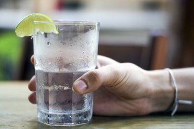 Erkek, su bardağını tutuyor.