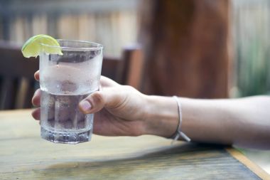 Erkek, su bardağını tutuyor.