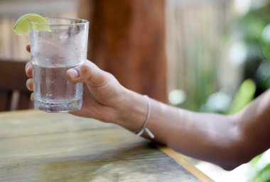 Erkek, su bardağını tutuyor.