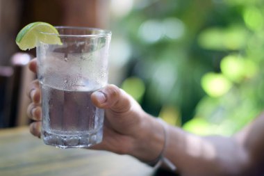 Erkek, su bardağını tutuyor.