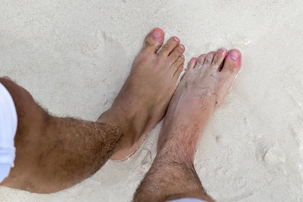 Man with feet in the tropical ocean