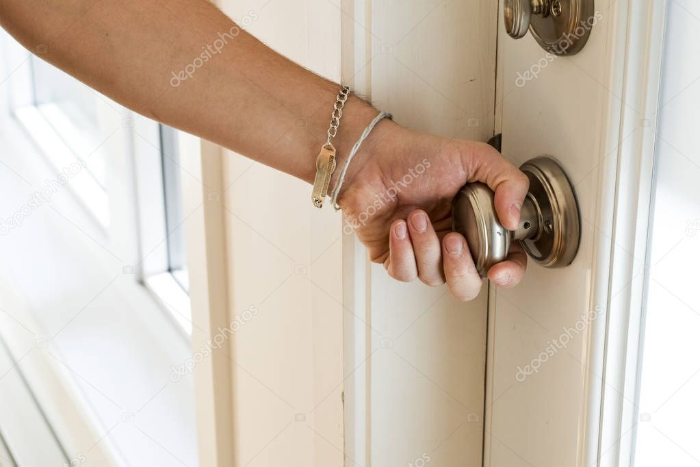 Male hand turning brass doorknob