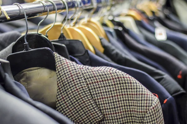 Rack of men\'s suit jackets hanging in boutique store