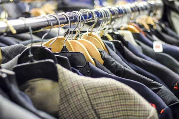 Rack of men\'s suit jackets hanging in boutique store