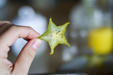 Starfruit dilim. Starfruit parçası üzerinde arka plan bulanık tutan erkek el.