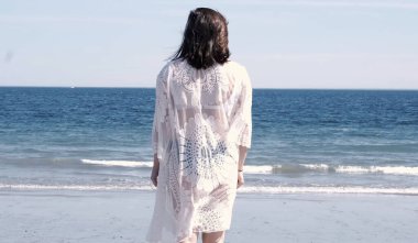 Kadın sakince durup okyanusa bakıyor. 4K yavaş çekim videosu.