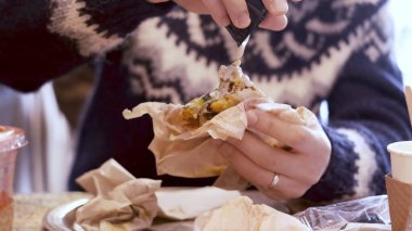 Adam öğle yemeği için restoranda falafel sandviçinin üzerine tahini döküyor. Yavaş çekim 4K video.