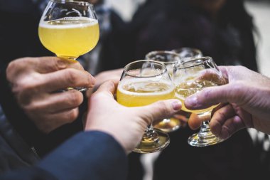 İnsanlar bira fabrikası turunda bira ile kadeh kaldırıyor.