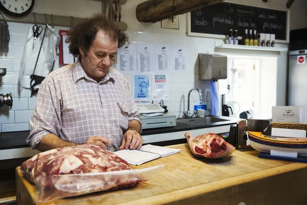 Butcher standing at counter of shop — Stock Photo, Image