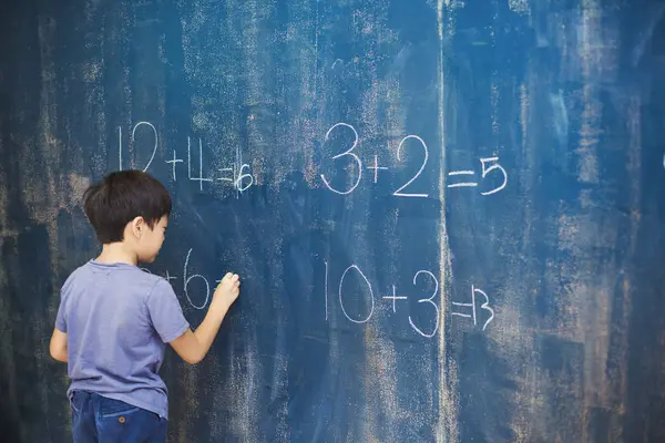 Boy writing in chalk on a chalkboard. — Stock Photo, Image