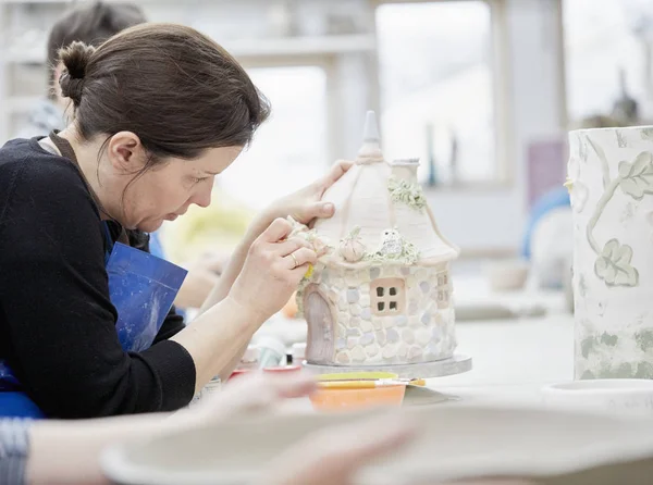 Vrouw bezig met gedecoreerde aardewerk cottage — Stockfoto