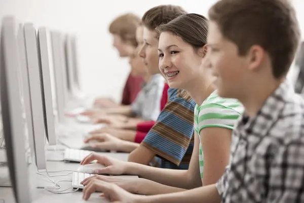 计算机教室中的男孩和女孩小组在显示器上工作 — 图库照片