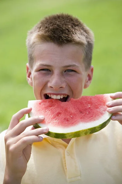 Teenage Boy Taking Bite Out Watermelon Slice Outdoors Looking Camera — Stock Photo, Image