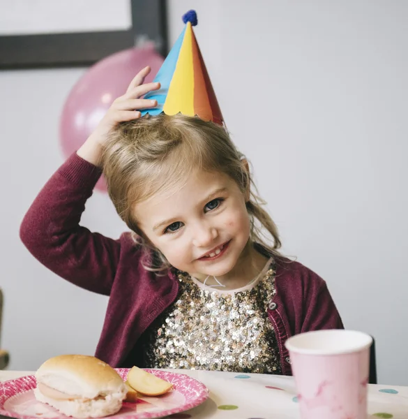 Fille dans un chapeau de fête à une fête d'anniversaire . — Photo de stock