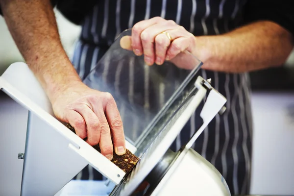 Carnicero rebanando salami con rebanadora - foto de stock