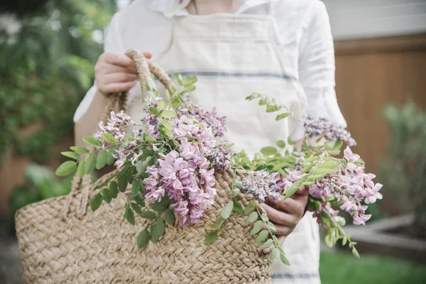 Woman with basket of pink flowers. — Stock Photo