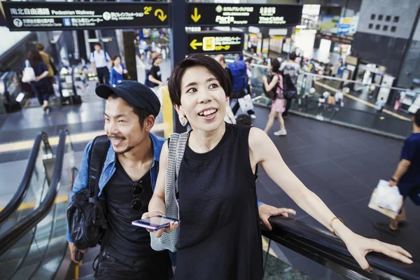 Uomo e donna in scala mobile in un centro commerciale . — Foto stock