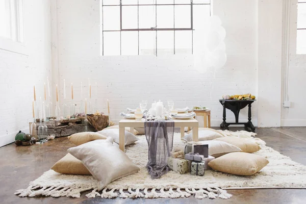 Apartment interior with table set for celebration with cushions on floor. — Stock Photo