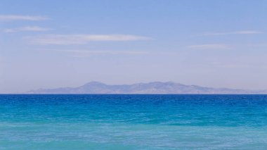 Sakin manzara. Deniz yüzeyi ve arka planda dağlar