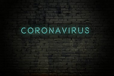 Brick wall with neon inscription Coronavirus