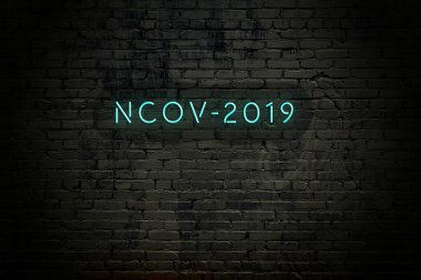 View of a brick wall with neon inscription nCov-2019