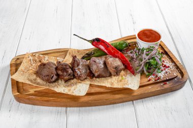 Izgara sebzeli biftek kebabı ve ahşap masada kırmızı sos. 