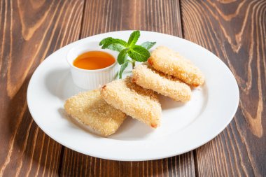 Bir tabak abur cubur. Kızarmış peynir, ballı ve nane şekerli ahşap masa.