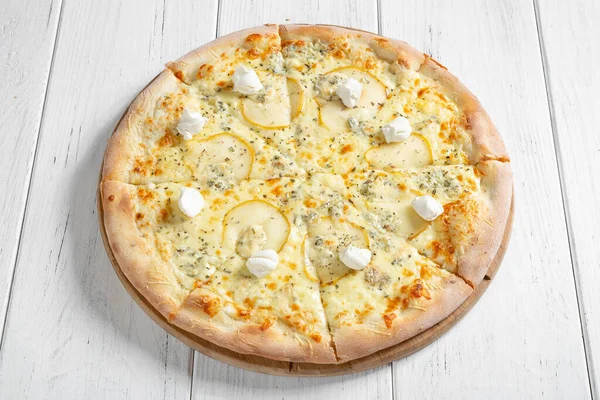 Fresh italian pizza with different types of cheese and slices of pear on wooden table