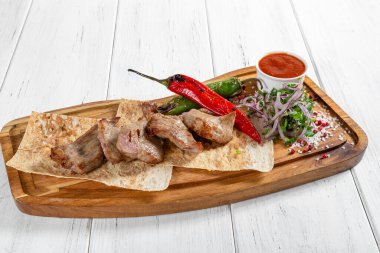 Sebzeli ızgara et kebabı ve ahşap masada kırmızı sos.
