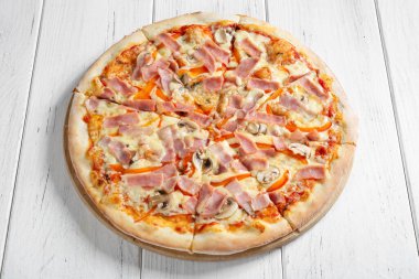 Beyaz ahşap masada jambonlu ve mantarlı taze İtalyan pizzası