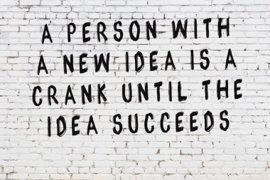 Beyaz tuğla duvar arkaplanına siyah düşünceli bir yazı.