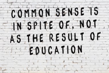 Beyaz tuğla duvar arkaplanına siyah düşünceli bir yazı.