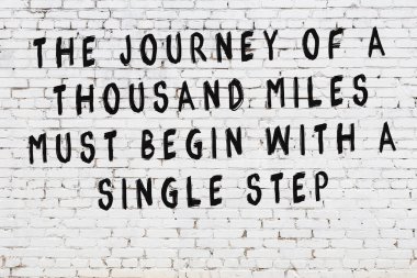 Beyaz tuğla duvar arkaplanına siyah düşünceli bir yazı.