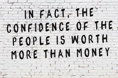 Beyaz tuğla duvara zekice alıntılar yazılı siyah bir yazı.