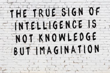 Beyaz tuğla duvar arkaplanına siyah düşünceli bir yazı.