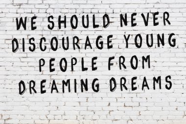 Beyaz tuğla duvar arkaplanına siyah düşünceli bir yazı.