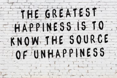 Beyaz tuğla duvar arkaplanına siyah düşünceli bir yazı.