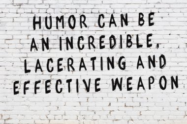 Beyaz tuğla duvara zekice alıntılar yazılı siyah bir yazı.