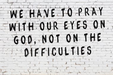 Beyaz tuğla duvara zekice alıntılar yazılı siyah bir yazı.