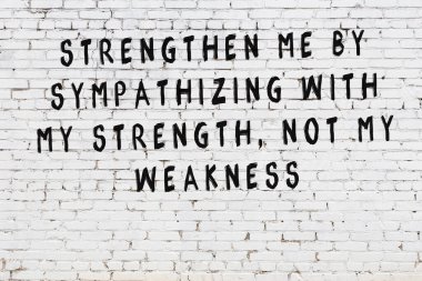 Beyaz tuğla duvara zekice alıntılar yazılı siyah bir yazı.