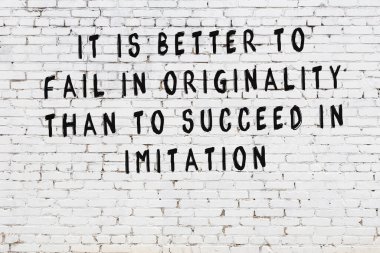 Beyaz tuğla duvar arkaplanına siyah düşünceli bir yazı.