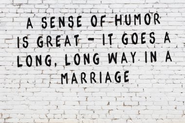 Beyaz tuğla duvara zekice alıntılar yazılı siyah bir yazı.