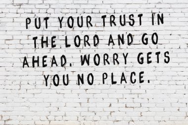 Beyaz tuğla duvara zekice alıntılar yazılı siyah bir yazı.