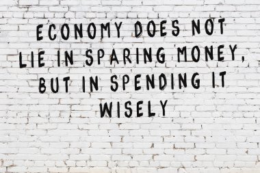 Beyaz tuğla duvara zekice alıntılar yazılı siyah bir yazı.